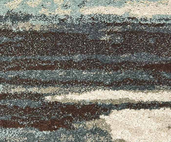 Close-up of the Oriental Weavers Carson / 9675A Rug, featuring contemporary wavy patterns in shades of blue, brown, and beige that evoke a natural landscape or abstract art. Crafted from durable polypropylene, this plush carpet combines style and comfort to enhance modern interiors.