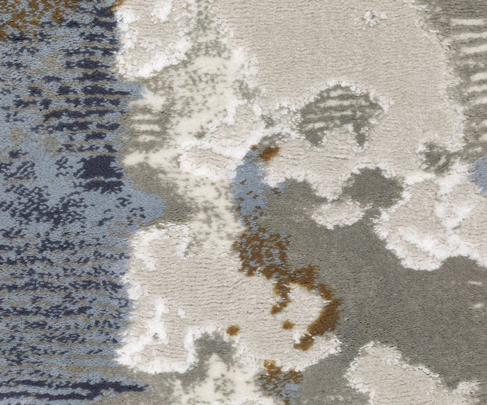 Close-up of the Oriental Weavers Easton 4518X Rug from the Easton Collection, featuring an abstract, cloud-like pattern in shades of gray, white, blue, and hints of brown. This durable power-loomed rug boasts a richly textured surface that brings contemporary style to any space.