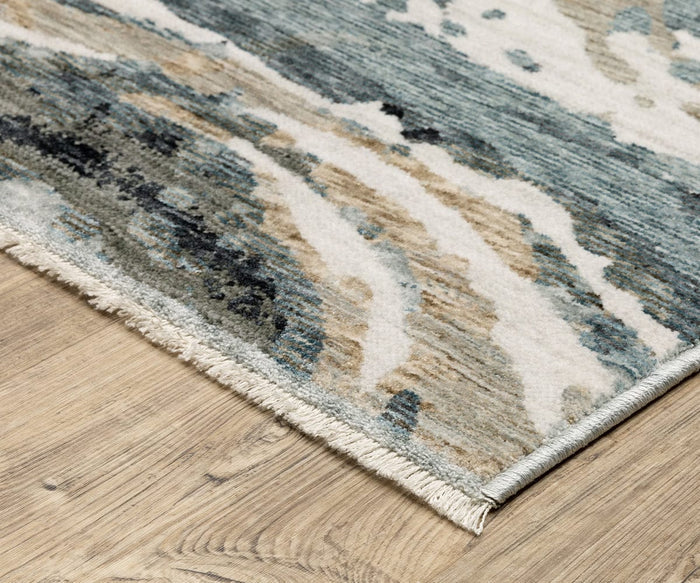 A close-up of the Oriental Weavers Echo / ECH07 Rug—a power-loomed rug made in Egypt—showing its textured surface with blue, beige, and cream abstract patterns on a wooden floor. The rug is accented with short fringe along the edge.
