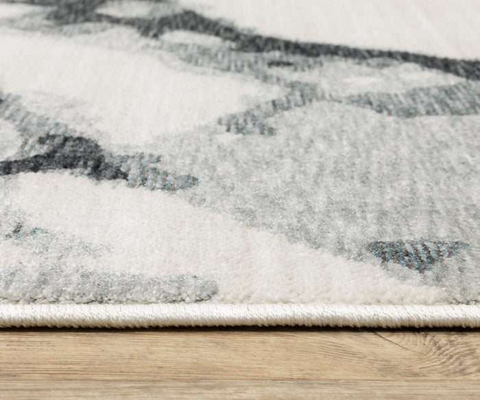 A close-up of the Oriental Weavers Echo / ECH08 Rug in gray and white tones shown on a wooden floor. The rug’s edge is clearly visible, showcasing its texture and low pile. Power-loomed in Egypt, this rug offers durability along with contemporary style.