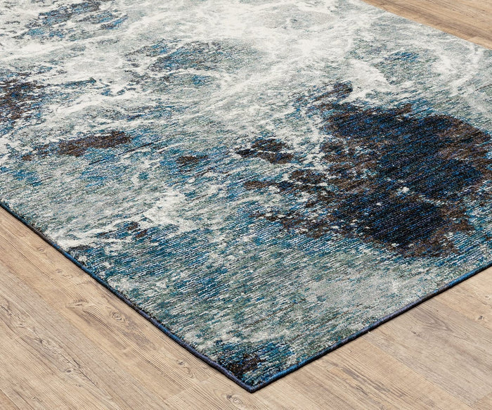 The Oriental Weavers Evolution / 962A Rug showcases a textured, marbled pattern in blue, gray, and black tones. Crafted from durable nylon for easy maintenance, this area rug from the Evolution Collection is displayed here on a light wood floor.