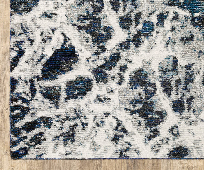 A close-up of the Oriental Weavers Evolution / 962A Rug showcasing its abstract pattern in shades of blue, gray, and white. This modern area rug from the Evolution Collection is crafted from durable nylon for easy maintenance and looks stunning on a light wood floor.