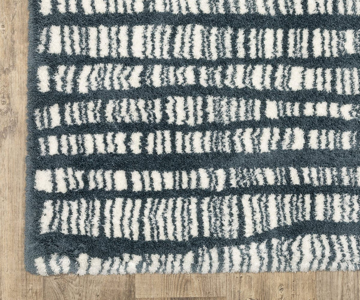 The Oriental Weavers Galileo GAL01 Rug, featuring a dark blue base and irregular white horizontal stripes in a textured, modern design, sits on a light wood floor; this rectangular area rug is crafted from dense pile microfiber polyester.