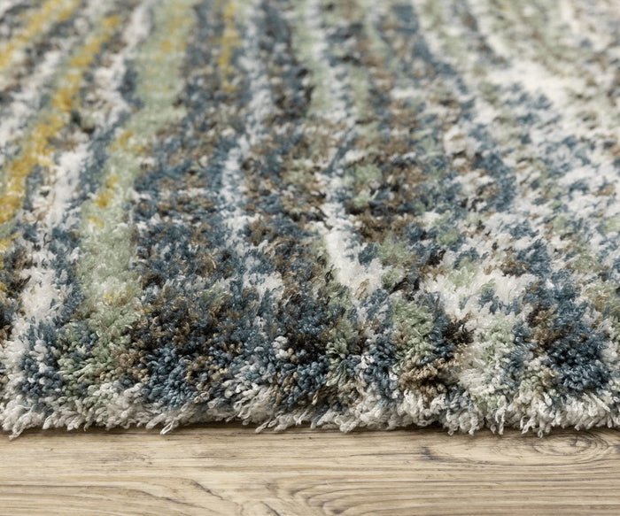 Close-up of the Oriental Weavers Galileo / GAL07 Rug, crafted from soft microfiber polyester fibers in blue, green, yellow, and white, shown on a light wood floor. The rug’s texture is fluffy and inviting with a dense pile construction for extra comfort.