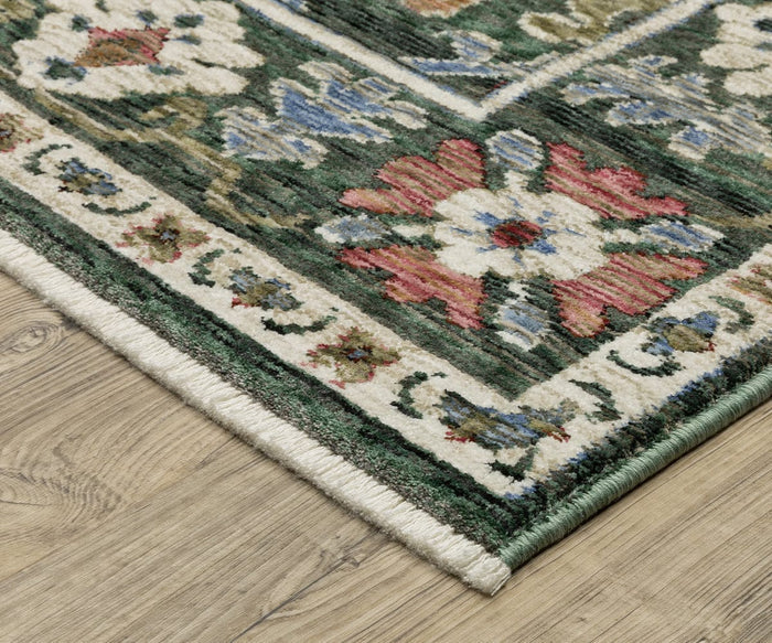 Corner of the Oriental Weavers Hastings / HA02B Rug, a patterned multicolor area rug featuring floral designs in red, white, blue, and green hues, displayed on a light wood floor. This space-dyed polyester rug includes a light-colored border decorated with small flower motifs.
