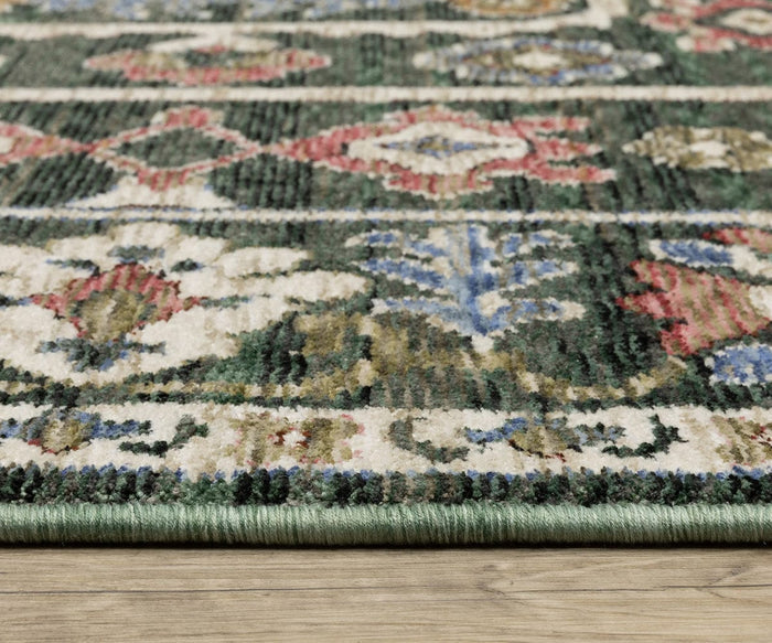 Close-up of the Oriental Weavers Hastings / HA02B Rug, featuring multicolor designs in green, cream, red, and blue on a textured space-dyed polyester surface, with the edge of the rug visible as it rests on a wooden floor.