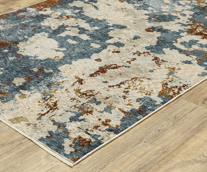 An Oriental Weavers Hayden / HAY01 Rug with a rectangular shape and abstract pattern in blue, beige, and brown hues rests on a light wood floor. Crafted from space-dyed polyester, this rug showcases a splashed or watercolor-inspired design.