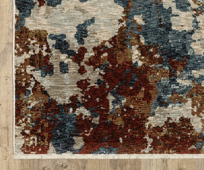 The Oriental Weavers Hayden / HAY01 Rug, showcasing an abstract pattern in rust, blue, gray, and cream hues, is displayed on a wooden floor. Crafted from space-dyed polyester for enhanced depth and texture, this rug features a modern uneven design with a visually dynamic appearance.
