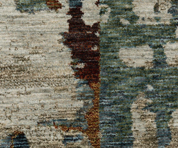 Close-up of a textured fabric featuring abstract patterns in blue, beige, brown, and green tones, reminiscent of a watercolor painting or the aged, distressed look of the Oriental Weavers Hayden HAY02 Rug.