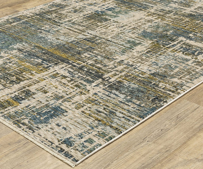 The Oriental Weavers Hayden HAY05 Rug showcases an abstract pattern in blue, green, beige, and yellow hues, sitting beautifully on a light wood floor. With its distressed, textured finish and irregular lines and shapes, this rug delivers a striking contemporary appeal.