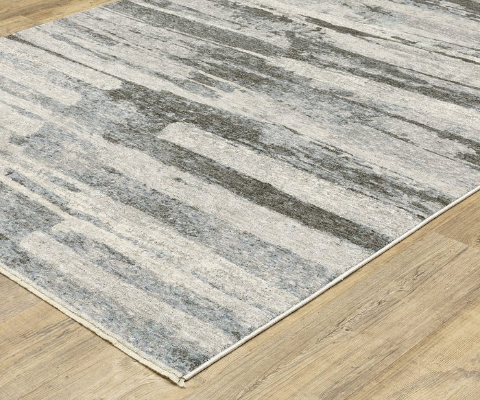 An Oriental Weavers Hayden / HAY07 Rug with a gray and white abstract pattern lies on a light wood floor. This modern area rug showcases irregular, abstract streaks and a slim border, crafted from soft space-dyed polyester for enhanced texture and visual depth.