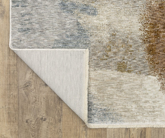 A corner of the rectangular Oriental Weavers Hayden / HAY09 Rug is flipped over to reveal the underside. This space-dyed polyester rug showcases an abstract pattern in muted tones and rests on a light brown wooden floor.