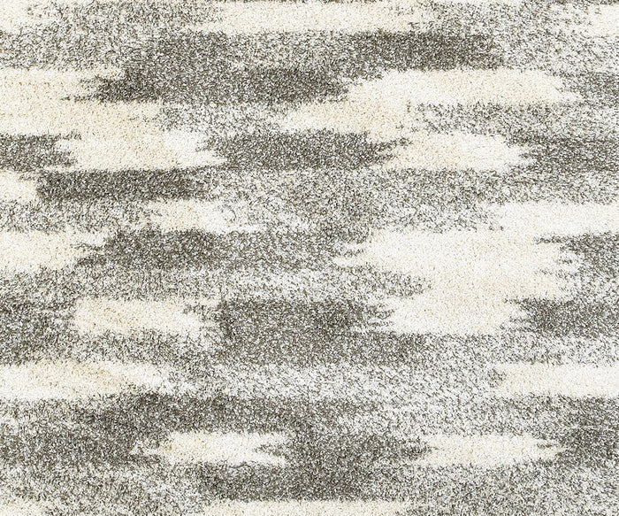 The Oriental Weavers Henderson / 565J Rug features an abstract pattern with irregular, cloud-like patches in shades of gray and cream, creating a textured, modern aesthetic. Ideal for those seeking neutral area rugs with a contemporary vibe, this design combines the soft comfort of shag rugs with the bold style characteristic of a modern geometric rug.