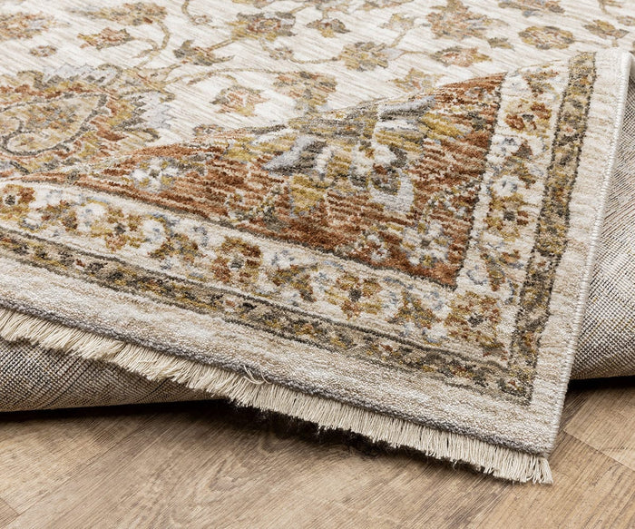 A close-up of a corner of the Oriental Weavers Maharaja / 5091Q Rug folded over, displaying its intricate floral pattern and fringe on a wooden floor.
