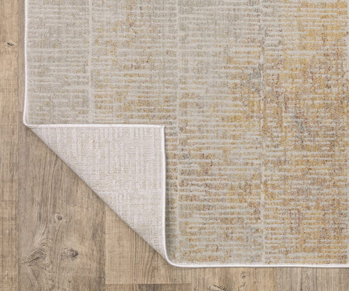 A corner of the light-colored Oriental Weavers Mallory / MAL09 Rug is flipped over on a wooden floor, revealing the contrasting texture and stitching of its space-dyed polypropylene underside and showcasing its subtle, power-loomed pattern.