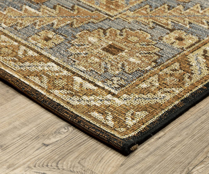 Corner of the Oriental Weavers Naples / 1441X Rug, showcasing intricate gold, beige, and brown patterns on a gray background atop a light wood floor. This durable polypropylene rug is suitable for both indoor and outdoor use, designed to be fade-resistant while bringing elegant style to your space.