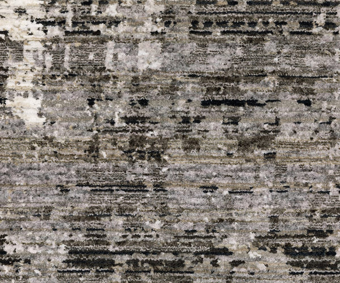 A close-up of the Oriental Weavers Nebulous / 4151N Rug highlights a textured, abstract pattern in shades of gray, black, brown, and white for a contemporary distressed look. This power-loomed polyester rug exemplifies the modern artistry of the Nebulous Collection.