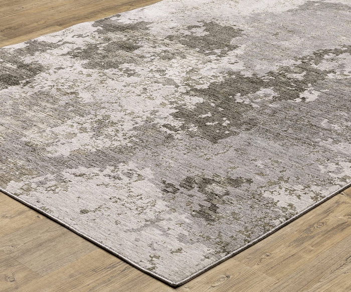 The Oriental Weavers Nebulous / 5091E Rug displays a textured, abstract gray and beige pattern on a light wood floor, crafted from soft polyester yarn. Its softly blended colors create a modern, distressed look that exemplifies the contemporary appeal of modern abstract rugs.