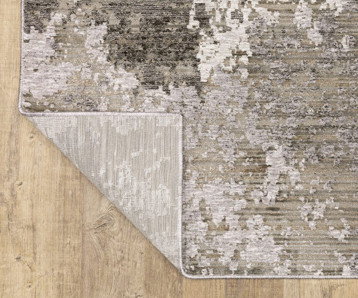 The Oriental Weavers Nebulous / 5091E Rug, showcasing abstract gray, beige, and cream patterns, is displayed on a light wood floor with one corner folded over to reveal its high-quality polyester yarn underside.