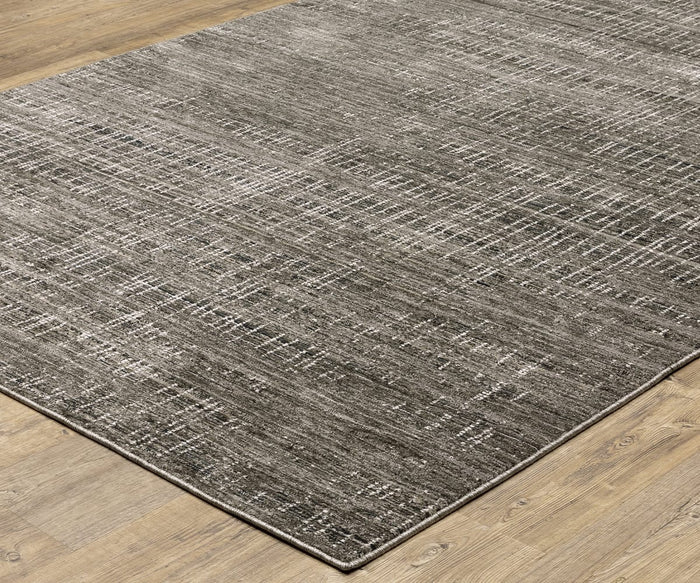The Oriental Weavers Nebulous / 751D Rug, a rectangular gray area rug crafted from space-dyed polyester, showcases a subtle linear and grid pattern as it rests elegantly on a light wood floor.