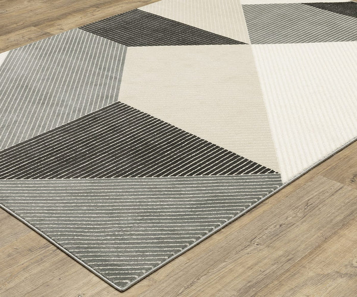 The Oriental Weavers Raylan / RAY07 Rug showcases modern geometric motifs in black, white, and gray tones, with distinctive diagonal and horizontal striped patterns and an eye-catching high/low construction, displayed on a light wood floor.