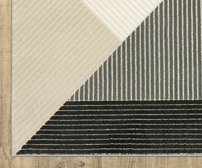 The Oriental Weavers Raylan / RAY07 Rug features a geometric pattern in beige, gray, and black sections accented by white vertical stripes and distinctive high/low construction, shown here on a wooden floor.