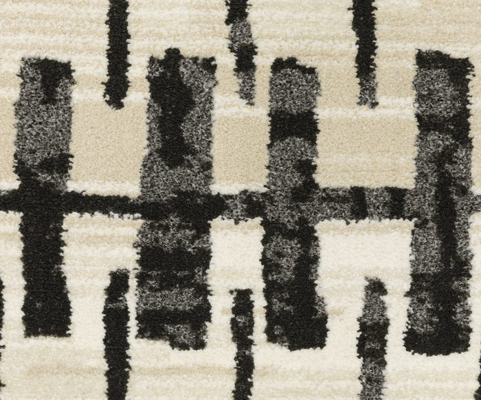 The Oriental Weavers Raylan / RAY11 Rug features bold, black brushstroke-like lines arranged vertically and horizontally across a cream and beige background. Its modern, artistic feel is enhanced by a subtle geometric motif and a fade-resistant design.