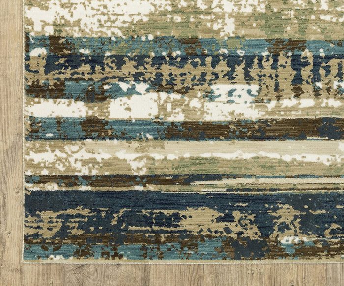 A corner of the Oriental Weavers Reed / RE02A Rug, with an abstract pattern in blue, beige, cream, and brown tones, crafted from space-dyed polypropylene and placed on a light wood floor. This textured rug features horizontal streaks and painterly details for added visual interest.