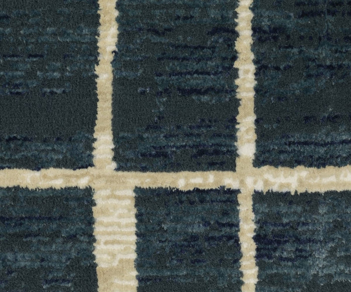 Close-up of a textured rug, specifically the Oriental Weavers Reed / RE04B Rug, featuring a dark blue background with beige grid lines forming large squares. Crafted from space-dyed polypropylene, its surface appears soft and plush.
