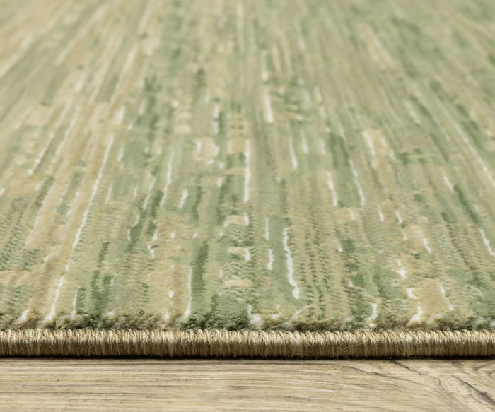 Close-up of the Oriental Weavers Reed / RE09A Rug in green and beige, crafted from space-dyed polypropylene with a textured, abstract pattern. The rug is shown on a wooden floor, highlighting its edge and intricate surface details.