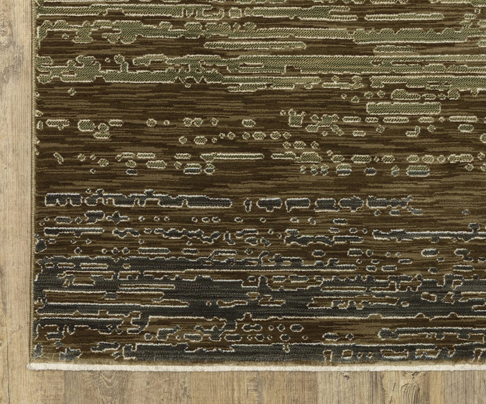 A close-up of the Oriental Weavers Reed / RE09A Rug showcases its abstract, horizontal green and brown patterns atop a wooden floor. This rug features varied, textured lines and dots, crafted from space-dyed polypropylene to provide both durability and rich visual depth.