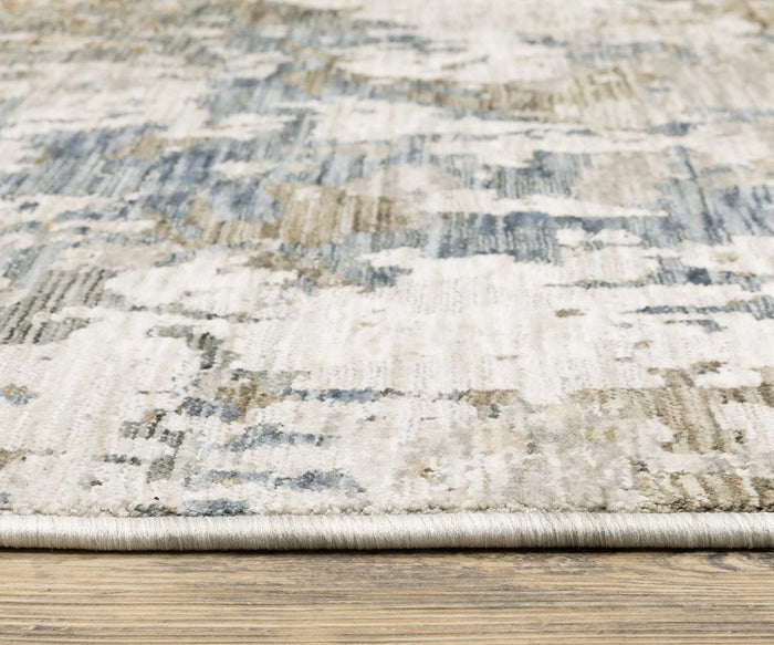 Close-up of the Oriental Weavers Soho / SOH03 Rug featuring abstract blue, beige, and gray patterns, shown on a wooden floor. Crafted from space-dyed polyester, the rug’s versatile palette is highlighted as its texture and edge detail are clearly visible.