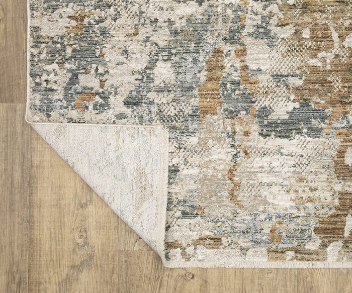 A corner of the Oriental Weavers Soho / SOH08 Rug is folded over on a wooden floor, exposing its underside. Crafted with space-dyed polyester yarns, this elegant décor rug showcases abstract patterns in shades of gray, beige, cream, and subtle hints of brown.