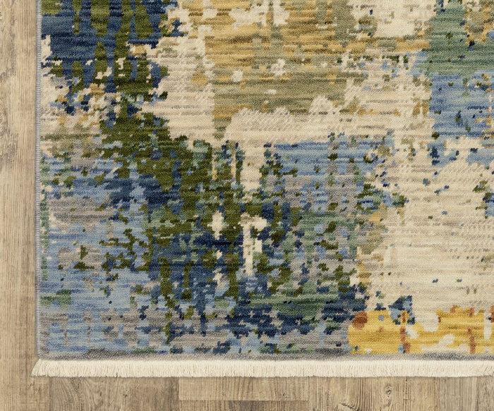 The edge of the Oriental Weavers Soleri / SOL01 Rug showcases an intricate modern abstract design in blue, green, yellow, and beige tones atop a light wood floor. Expertly crafted from a premium wool nylon blend on an Axminster loom, this rug features a white fringe accent along the bottom edge.