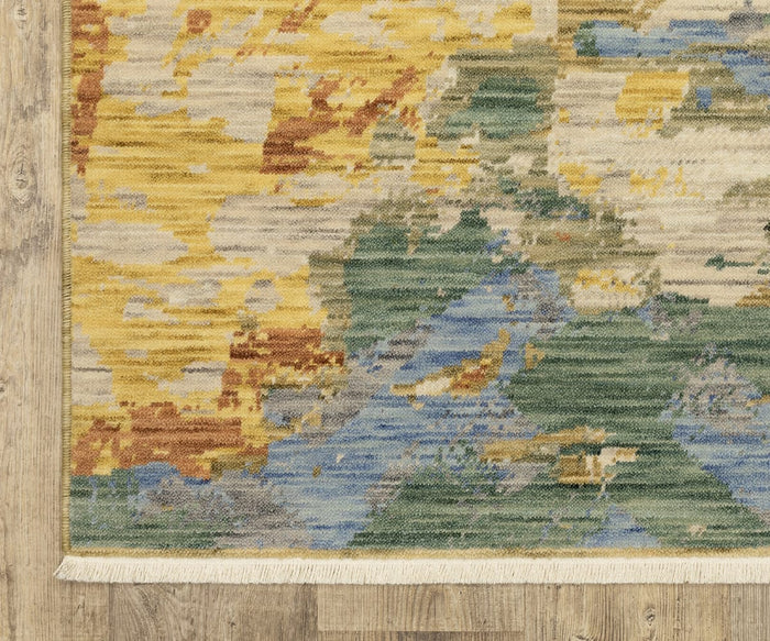 A close-up of the Oriental Weavers Soleri / SOL04 Rug from the Soleri Collection shows its yellow, green, blue, and brown abstract patterns on light wood flooring. This modern rug is crafted from a durable blend of wool and nylon and features a cream fringe along the edge.
