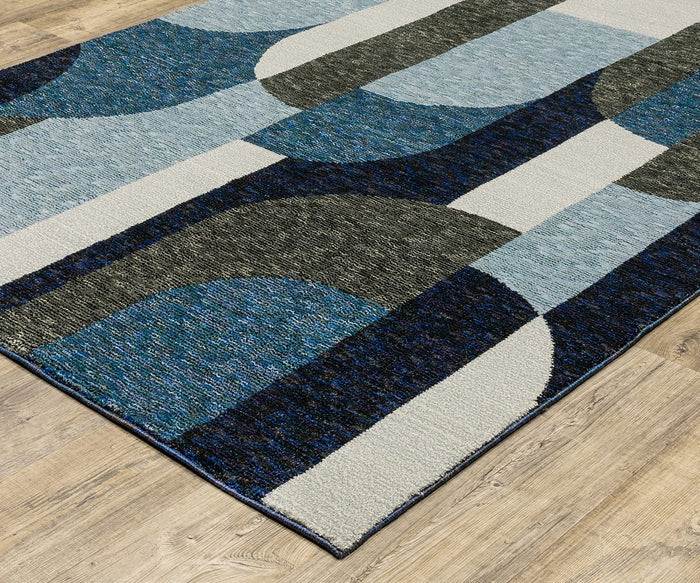The Oriental Weavers Strada / STR03 Rug, featuring overlapping geometric shapes in blue, gray, and cream tones, adds a sophisticated touch to modern spaces and beautifully complements the wooden floor.
