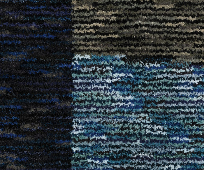 Close-up of the Oriental Weavers Strada / STR03 Rug, a machine-woven nylon carpet showcasing two distinct sections: the left side displays deep blue and black tones, while the right features horizontal stripes in blue, turquoise, gray, and white—ideal for introducing a bold pattern to modern spaces.