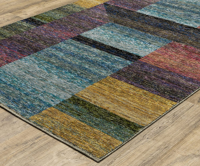 A close-up of the Oriental Weavers Strada / STR04 Rug, showcasing its colorful rectangular Art Deco patchwork design in blue, yellow, red, purple, and green. Crafted from machine-woven nylon and displayed on a light wood floor, this rug is perfect for adding vibrant style to modern spaces.