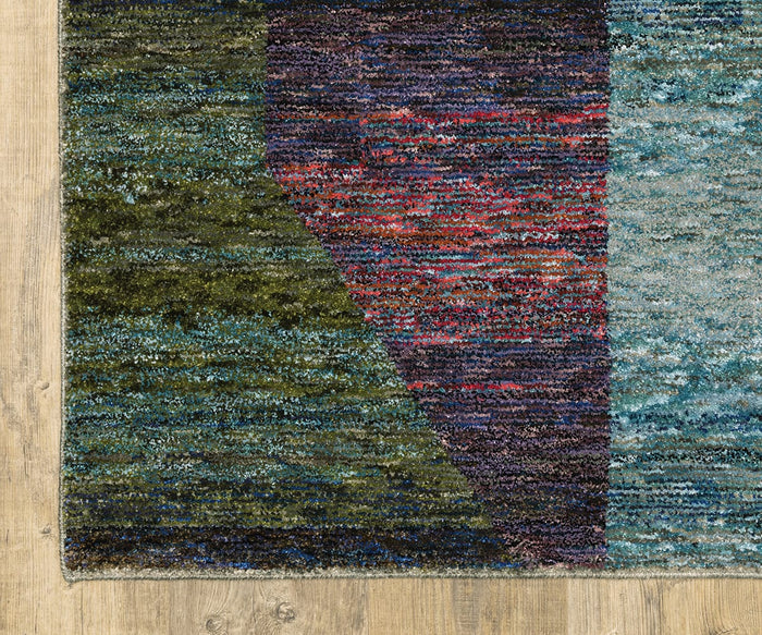 A close-up of the Oriental Weavers Strada / STR04 Rug showcases its colorful Art Deco design, featuring textured green, blue, and red sections on a machine-woven nylon surface. Displayed on a light wooden floor, only a corner of the rug is visible in the image, highlighting its suitability as an accent piece for modern interiors.
