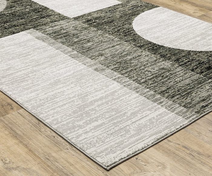 The Oriental Weavers Strada / STR06 Rug showcases a gray and white geometric design with rectangles and partial circles, set against a light wood floor. Its machine-woven nylon construction lends a subtle textured appearance, making it an excellent addition to contemporary interiors.
