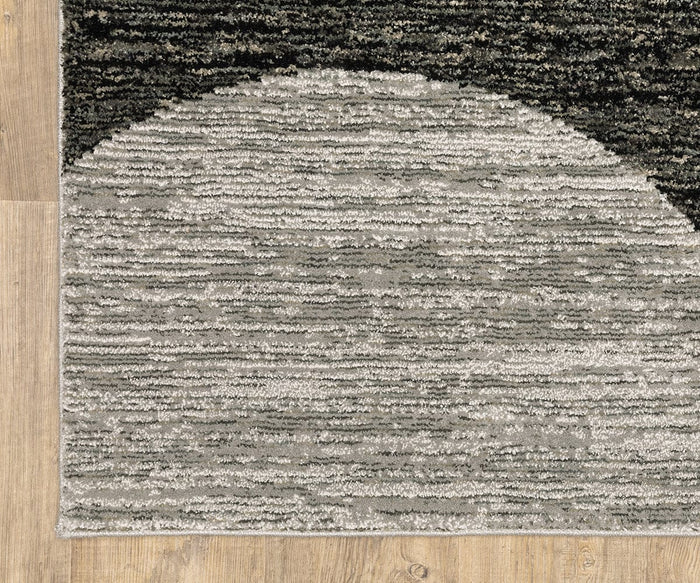 Corner of the Oriental Weavers Strada / STR06 Rug featuring a textured Art Deco design with a light gray half-circle, dark gray and black stripes above, and set on a light wooden floor—perfect for modern spaces and expertly crafted from machine-woven nylon.