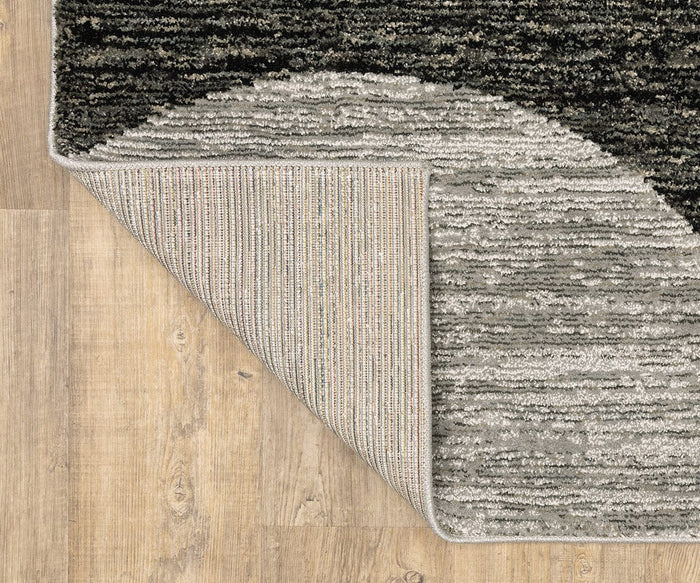 A corner of the Oriental Weavers Strada / STR06 Rug is flipped over on a wooden floor, revealing both the front and back sides of this machine-woven nylon rug—an ideal choice for bringing visual interest to modern spaces with its textured, striped Art Deco design.