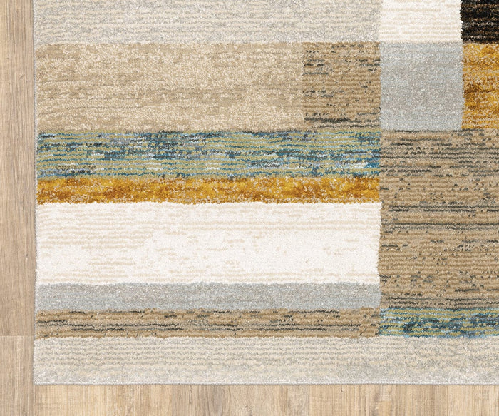 The Oriental Weavers Strada / STR07 Rug is a machine-woven nylon rectangular area rug featuring abstract color blocks and stripes in beige, cream, gold, blue, gray, and brown tones. It is shown placed on a light wood floor—perfect for modern spaces.