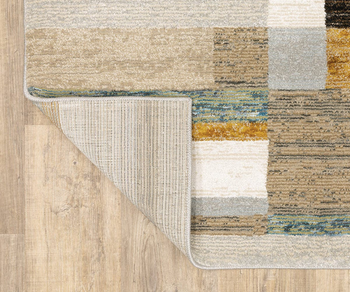The Oriental Weavers Strada / STR07 Rug is a multicolored, machine-woven nylon area rug with one corner flipped to display its textured underside. Perfect for modern spaces, it sits atop a light wooden floor and showcases beige, brown, blue, and gold rectangular sections inspired by Art Deco rug designs.