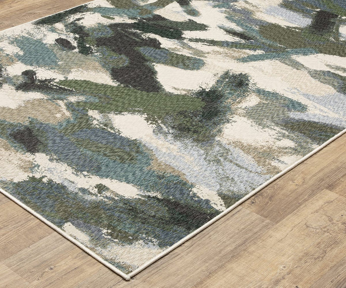 The Oriental Weavers Tisdell / TIS04 Rug features a striking blend of green, blue, cream, and black brushstroke patterns set against a light wood floor. Ideal for anyone seeking vibrant jewel tone rugs, this modern abstract area rug is crafted from durable polyester to ensure lasting style and comfort.