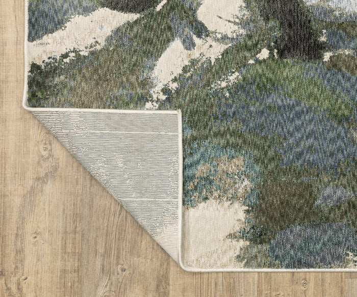 The Oriental Weavers Tisdell / TIS04 Rug, with its vibrant jewel tones and multi-colored green, blue, and cream abstract patterns, is displayed on a light wood floor. One corner of this modern rug is flipped over to showcase its durable polyester backing.