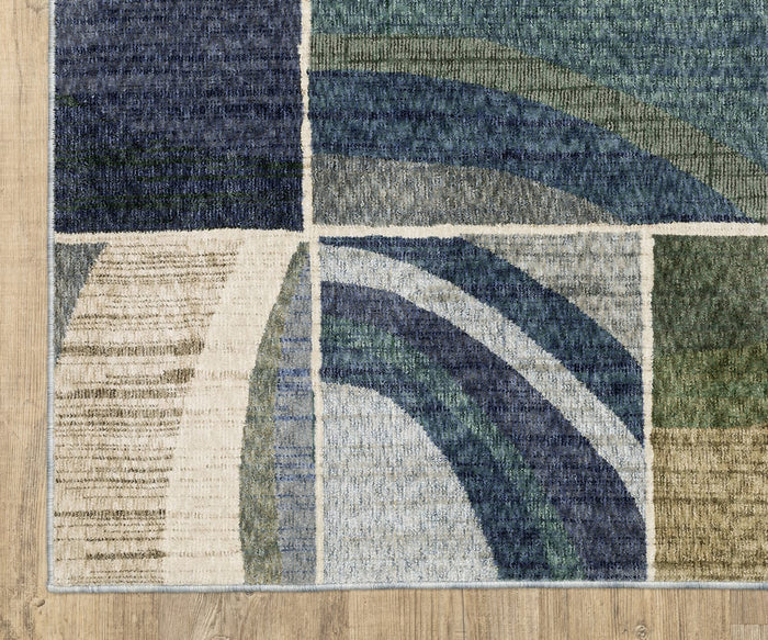 The Oriental Weavers Tisdell / TIS06 Rug, showcased on a wooden floor, displays abstract geometric shapes and curved lines in shades of blue, green, beige, and cream. Crafted from space-dyed polyester for lasting durability, this area rug brings artistic flair and contemporary style to any living space.
