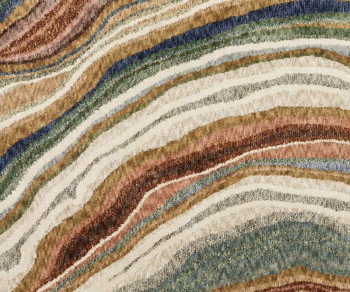 The Oriental Weavers Tisdell / TIS07 Rug features an abstract pattern of wavy, layered lines in earthy tones—beige, brown, green, blue, and touches of rust—that evoke the natural striations found in stone or minerals. Perfect for those seeking a modern abstract rug that combines artistic flair with organic inspiration.