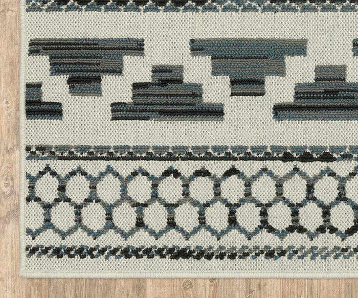 A section of the Oriental Weavers Torrey / 005Y1 Rug showcases geometric patterns in blue, black, and white on a light background. Featuring dynamic texture as part of the Torrey Collection, this rug is displayed on a light wood floor.