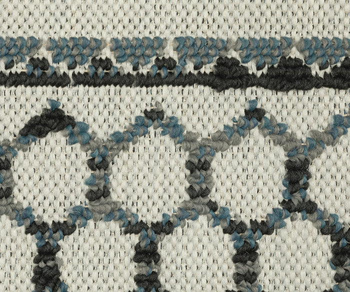 Close-up of the Oriental Weavers Torrey / 005Y1 Rug, showcasing a textured cream background adorned with abstract motifs in black, blue, and gray yarn that create interconnected shapes and lines for a dynamic texture.